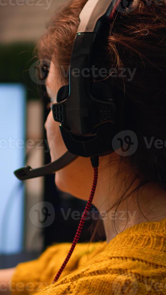Gamer playing game on championship discussing with teammates using mic of headset. Pro-gamner performing on powerful computer in stylish room during esport gaming tournament photo