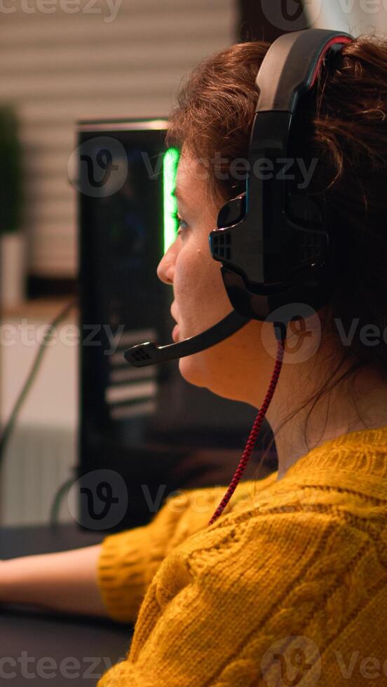 Professional esport woman gamer using mic of headset talking playing shooter game with team on streaming services. Virtual shooter game in cyberspace, esports player performing on pc gaming tournament photo