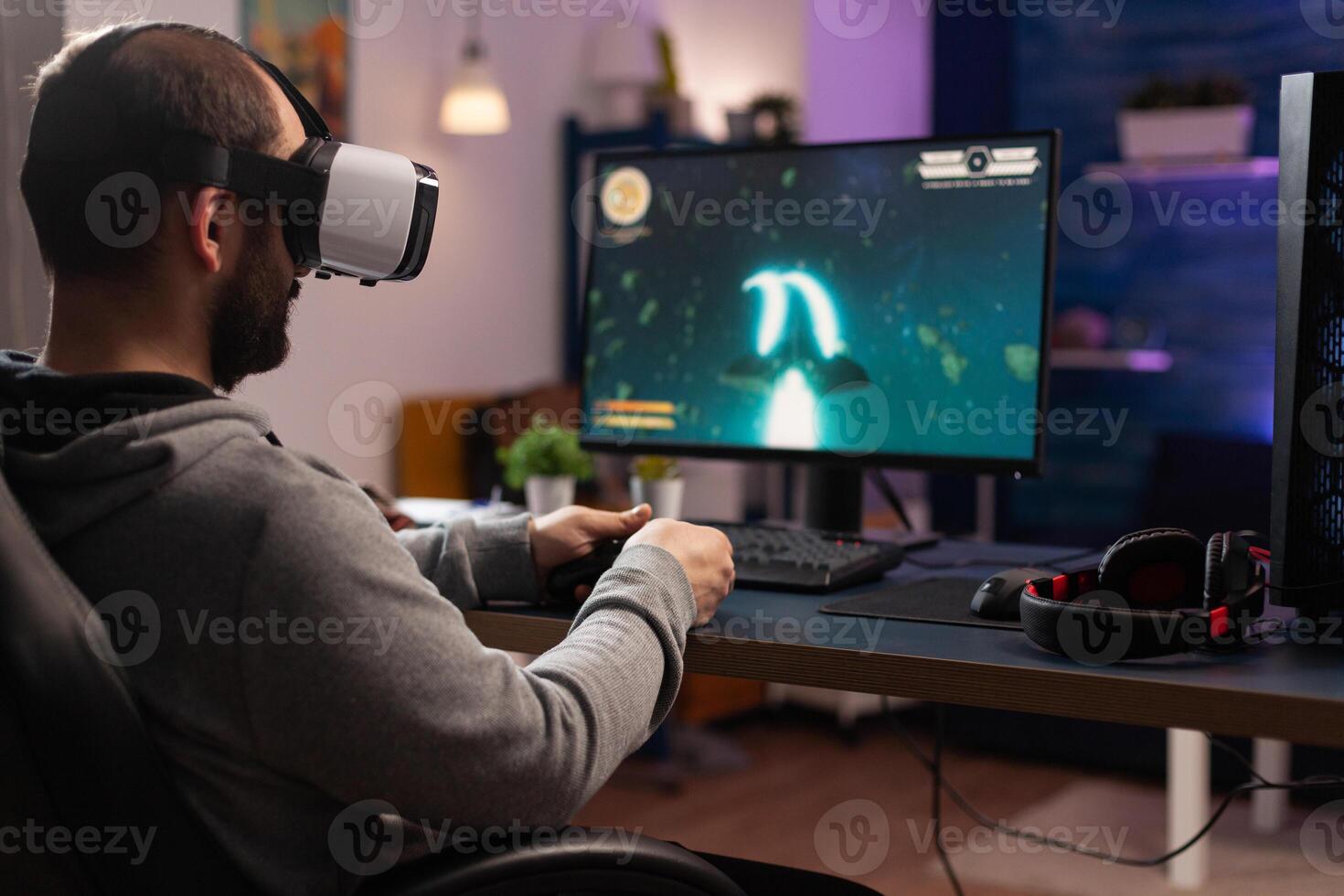Adult playing games with vr glasses on computer, using gaming equipment. Man with virtual reality headset holding joystick to play online games. Player using controller for game photo