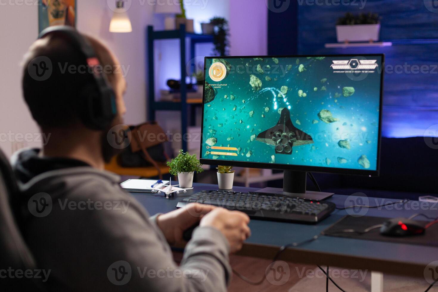 Man playing games with controller and headphones on computer. Player using joystick and audio headset for online gaming. Gamer having fun activity with equipment to play games. photo