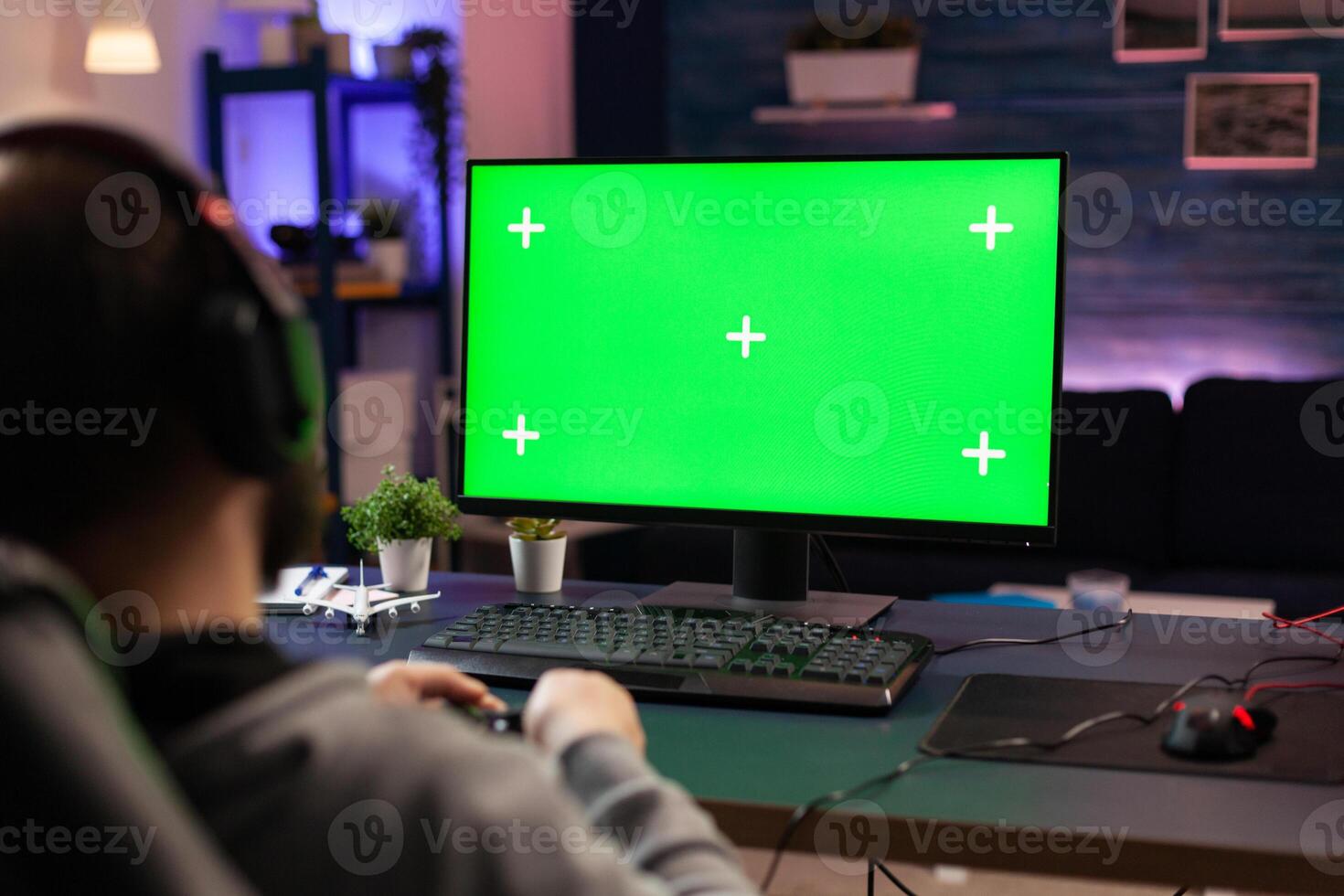 Gamer using horizontal green screen on computer. Man playing games on chroma key with isolated mockup template and background on display. Player with technology and equipment. photo