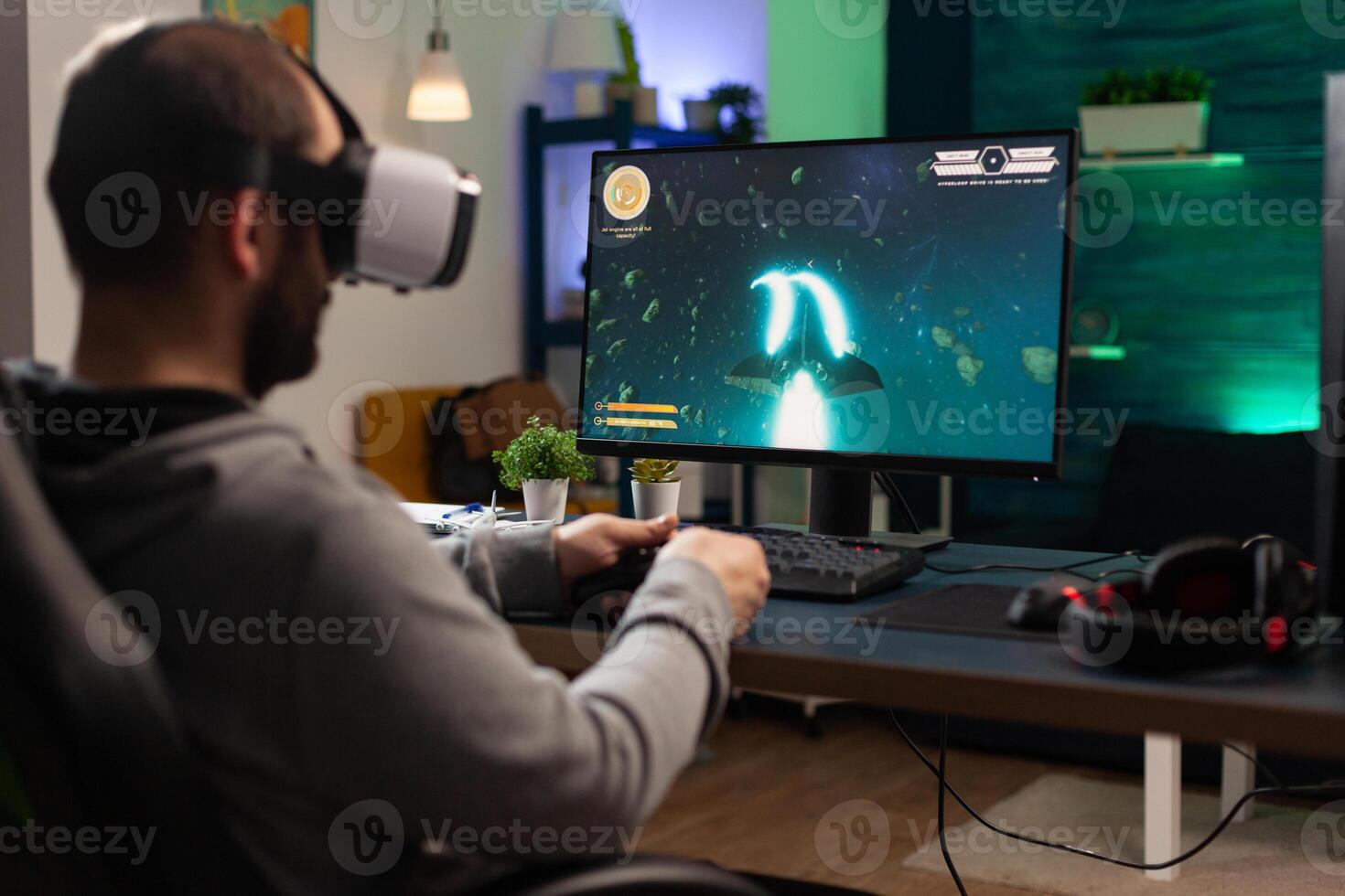 Man playing games with vr headset on computer, using gaming equipment. Gamer with virtual reality glasses holding joystick to play online games. Player using controller for game photo
