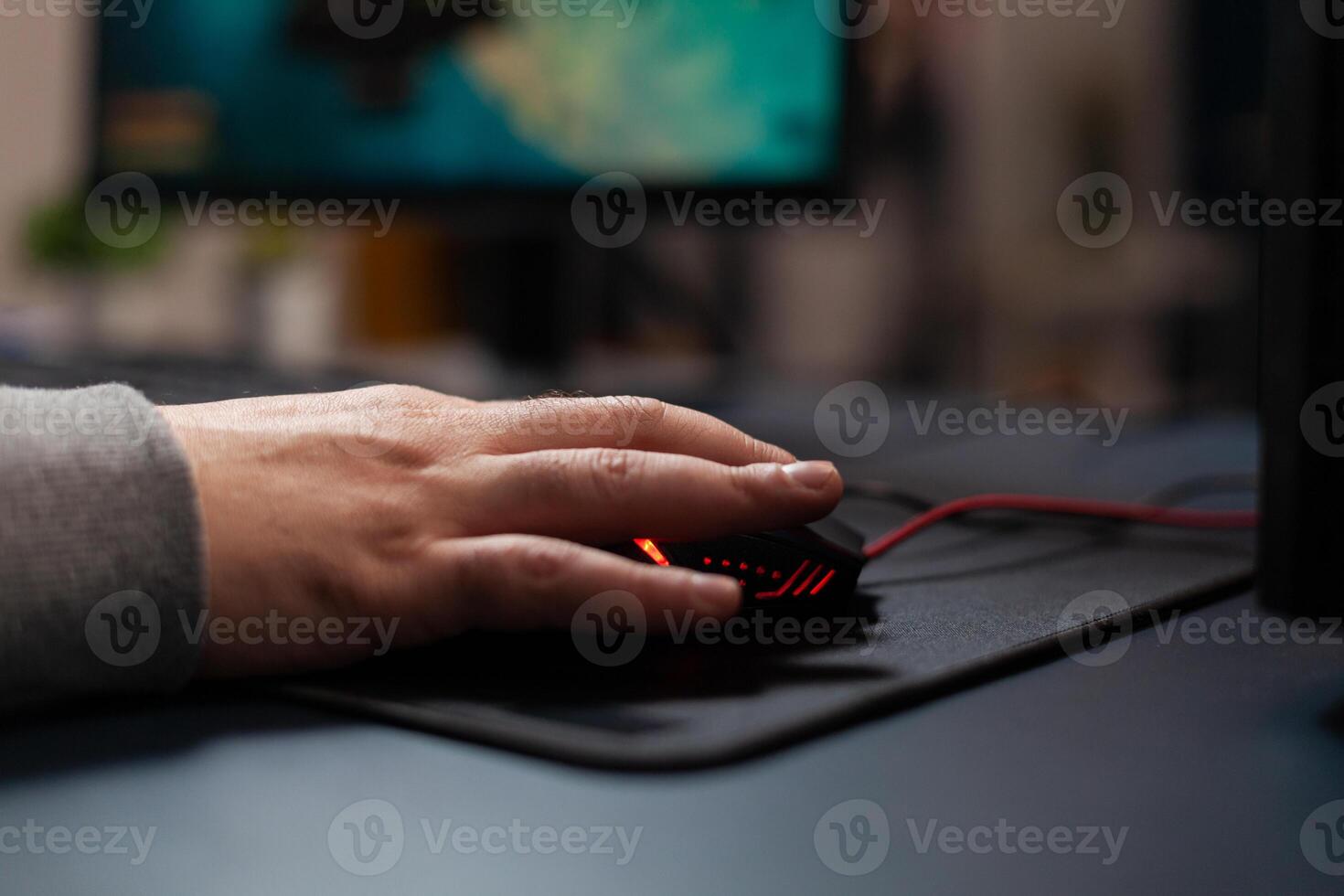 Close up of gamer holding mouse on mousepad to play games. Man using gaming equipment on computer, playing online game at desk. Hand of player on gadget having fun with games photo