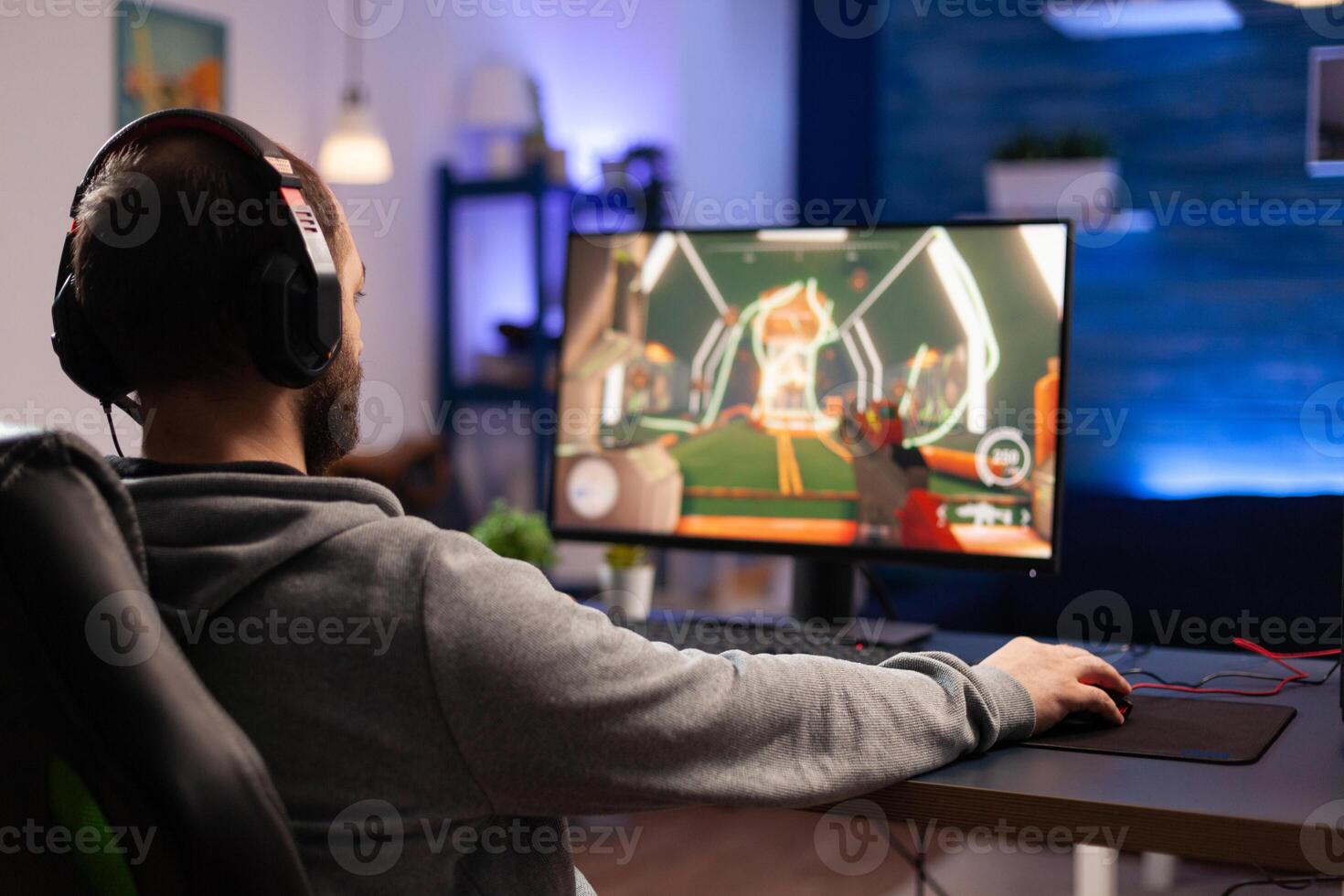 Player using keyboard and mousepad to play games on computer. Man wearing headphones and playing online game with mouse and gaming equipment. Gamer doing activity for entertainment photo