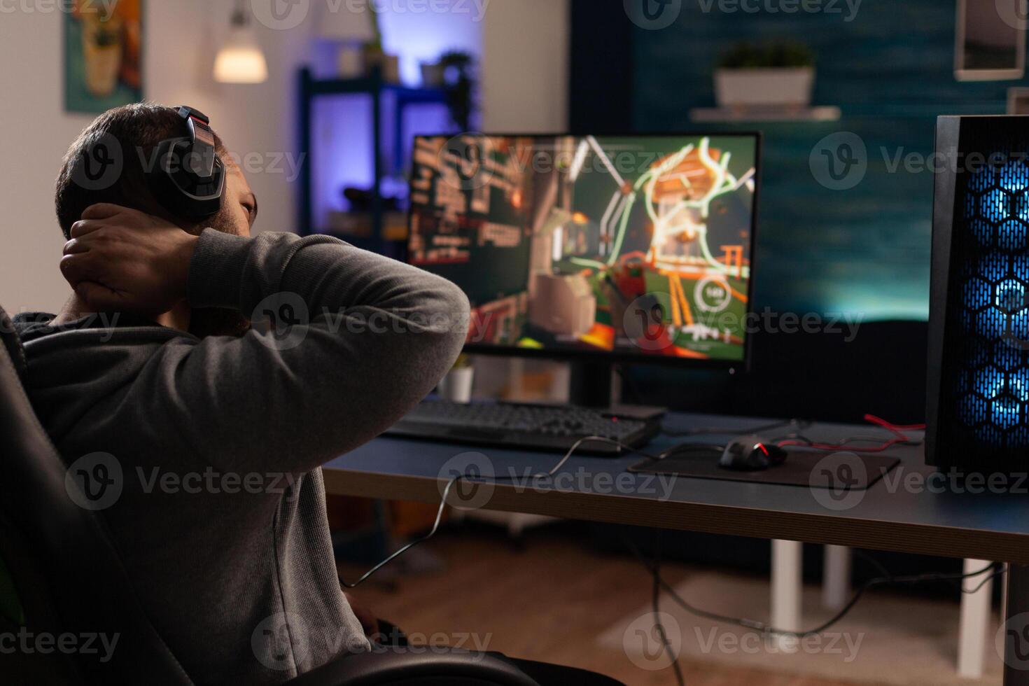 Adult preparing to play games on monitor, using headphones and gaming equipment. Man playing online games with keyboard and mousepad for fun and leisure. Electronic activity photo