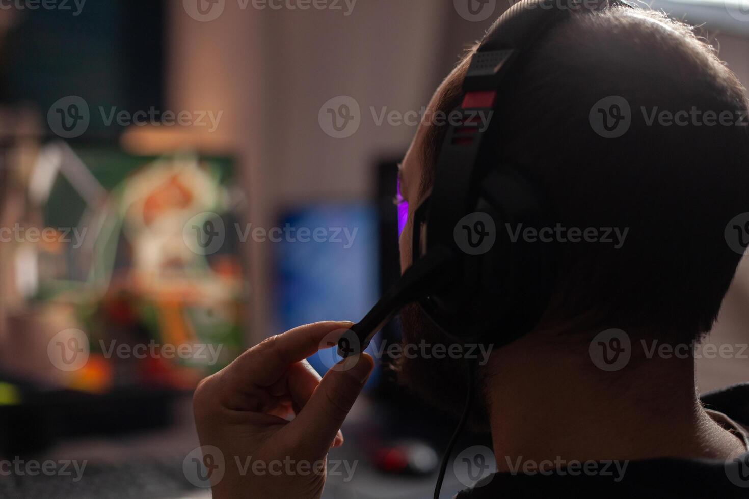 Close up of person streaming using microphone on headphones with computer. Man live streaming games play on monitor, talking to audience and playing online games for social media. photo