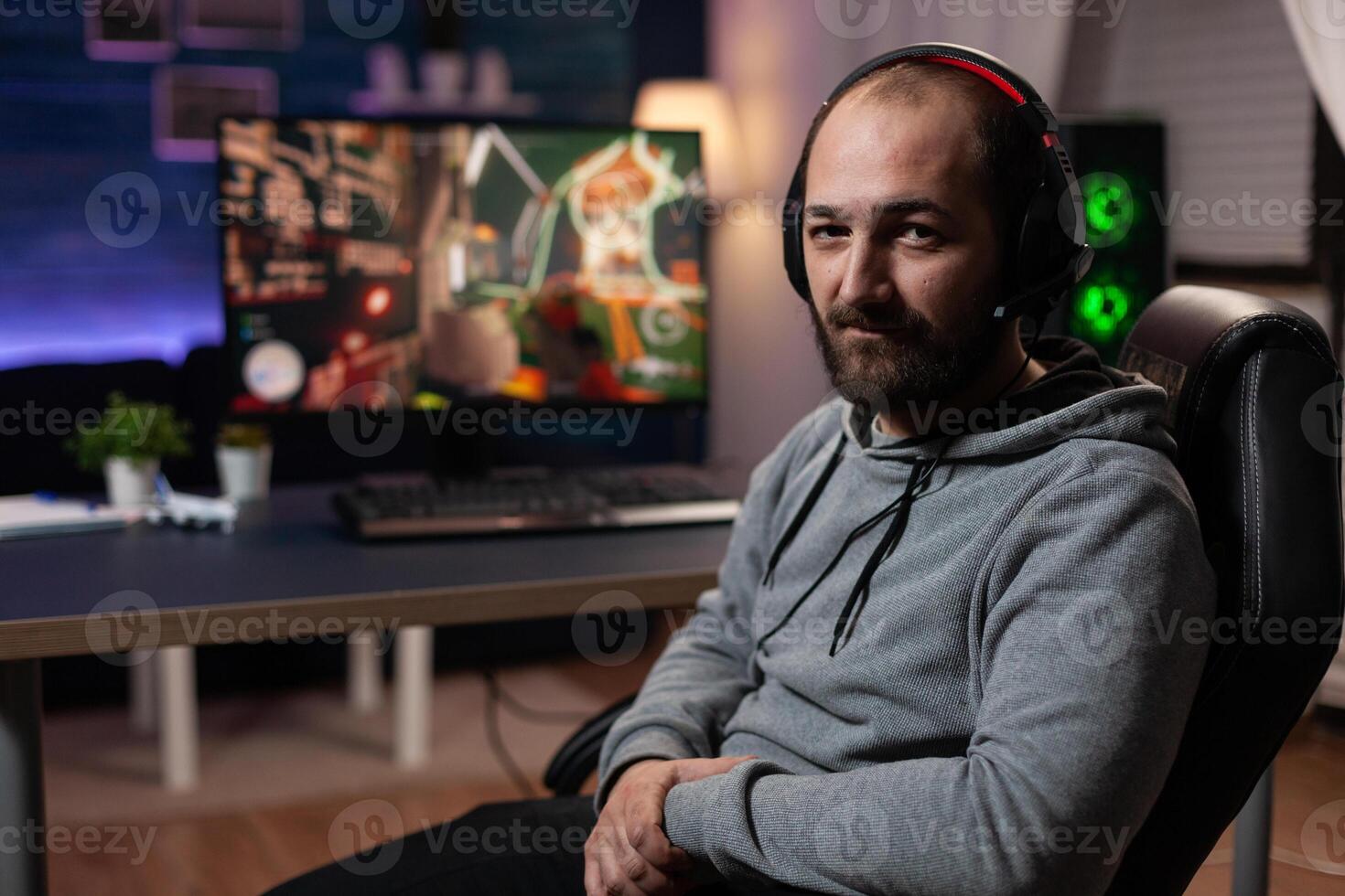 Portrait of man preparing to play games on computer. Gamer with headphones getting ready to stream live gameplay, playing with keyboard and mousepad on monitor. Player streaming photo