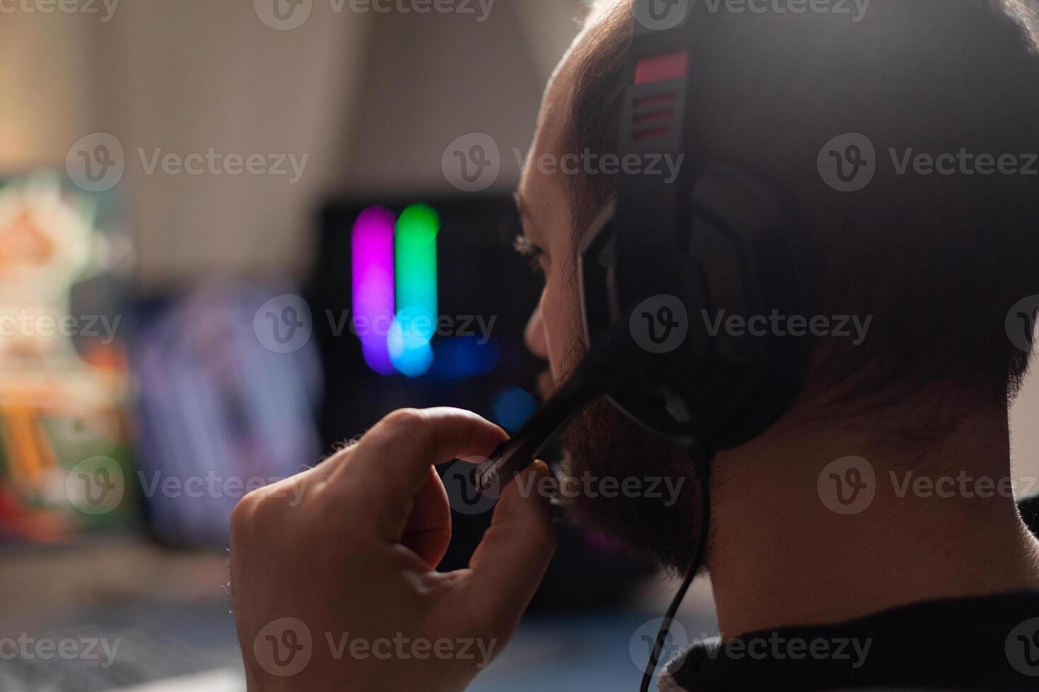 Close up of man using microphone on headphones to stream with computer. Gamer live streaming games play on monitor, talking to audience and playing online games for social media. photo