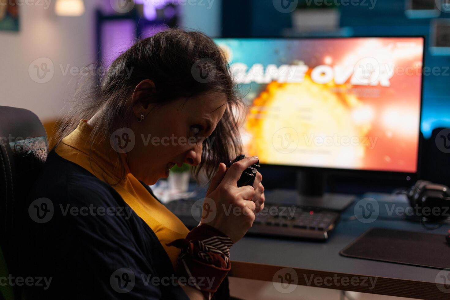 Frustrated gamer playing online games with controller. Woman using joystick on computer to play internet games and losing. Disappointed person with electronic gaming equipment. photo