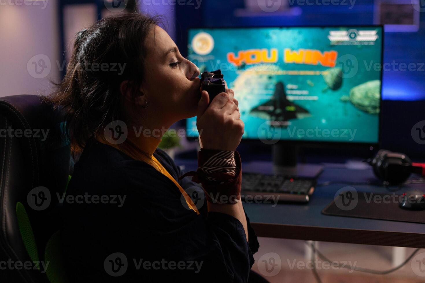 Cheerful adult kissing controller after winning games. Woman feeling happy about win, using joystick on computer to play online game. Gamer with technology playing on internet. photo