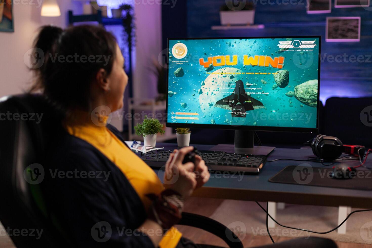 Gamer using controller to play games on computer. Happy woman winning online games with joystick in front of monitor. Person feeling cheerful and celebrating win on internet. photo