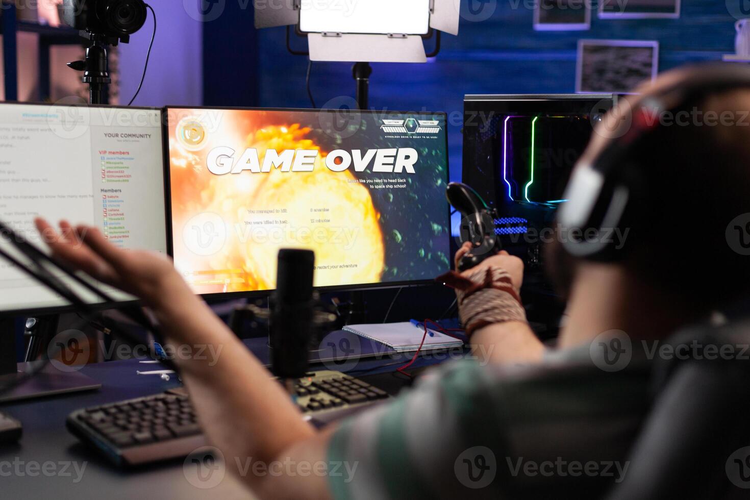 Player streaming games with headset and losing on computer. Man looking at monitors with live stream chat and online game, playing and broadcasting gameplay with microphone. photo