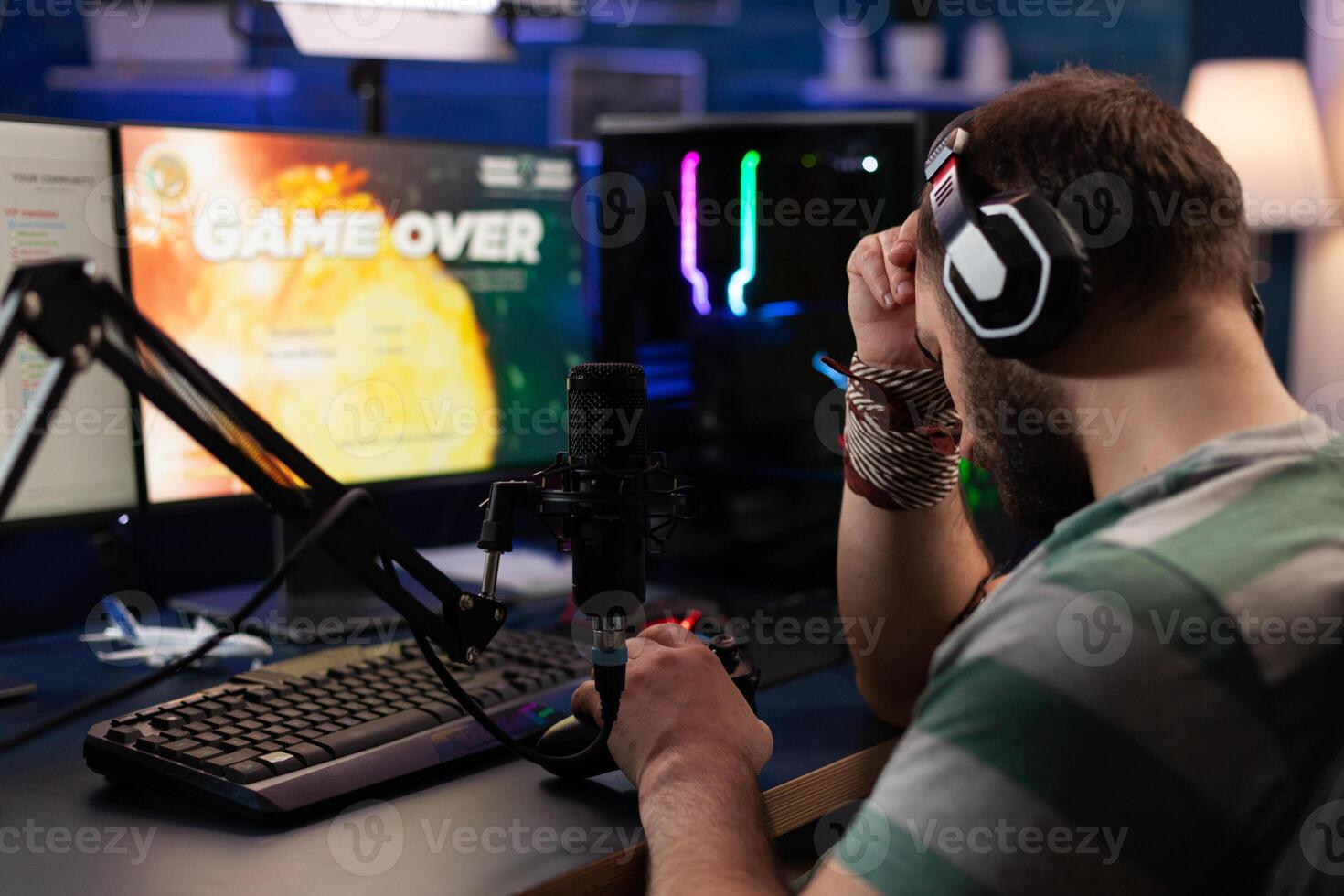 Man losing games and streaming with live chat on computer. Person showing gameplay on online stream with microphone and headphones. Player live streaming digital games on monitor. photo