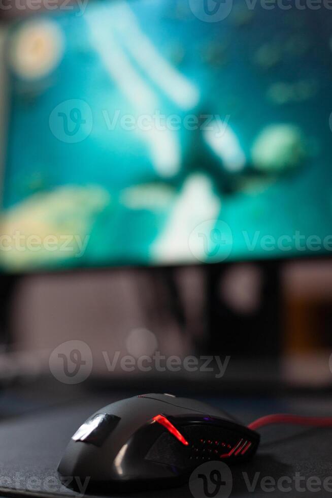 Close up of mouse in front of computer on desk. Mousepad and gaming equipment used to play games online on monitor. Game on digital cyberpace with modern gadgets on table. photo