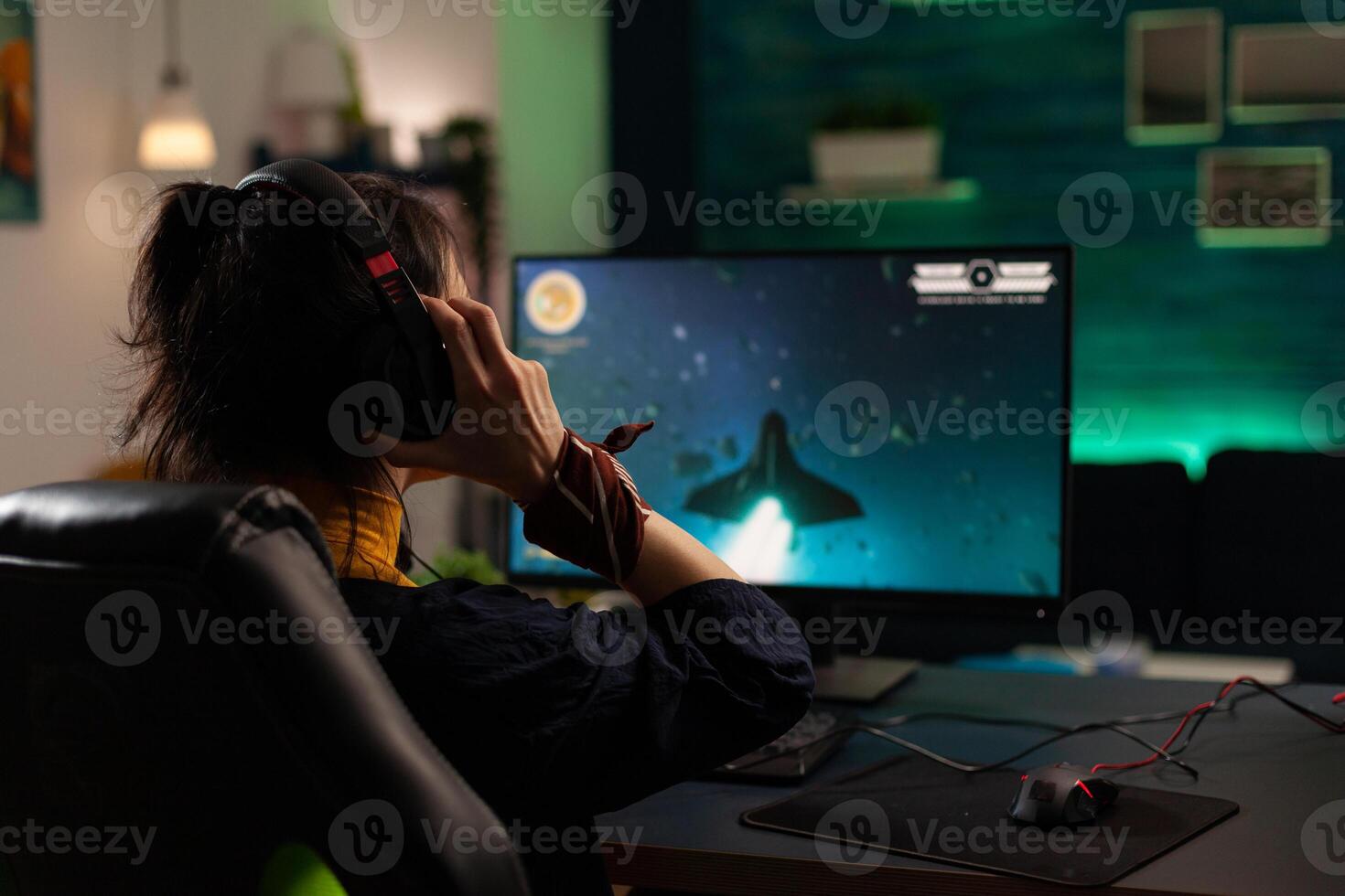 Woman using headphones to stream games play on computer. Gamer live streaming gameplay with headset and monitor. Player broadcasting game in cyberspace with modern equipment. photo
