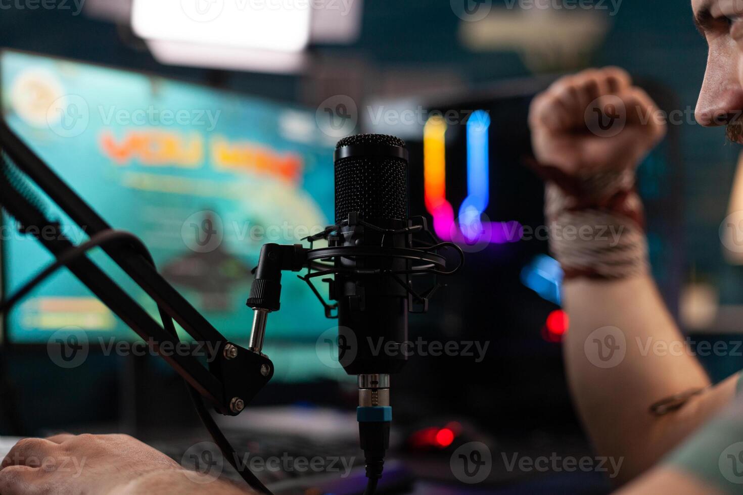 Close up of man winning games on stream with live chat, celebrating win and live streaming gameplay. Streamer using headphones and microphone on computer to broadcast and play. photo