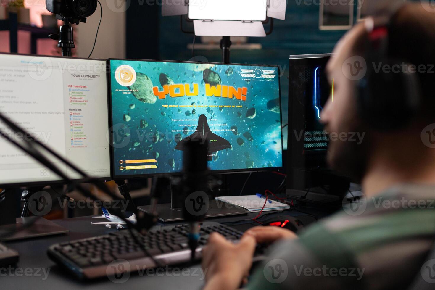 Streamer playing games with controller on computer. Man live streaming gameplay and winning, using microphone and headphones while he talks to online chat on monitor. Gamer on stream photo