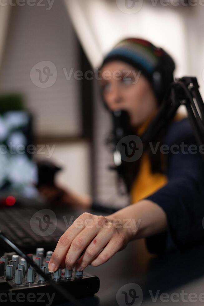 Close up of adult using streaming equipment on desk with headphones and microphone. Gamer talking to audience on broadcast, live streaming on computer. Streamer with electronic gadget photo