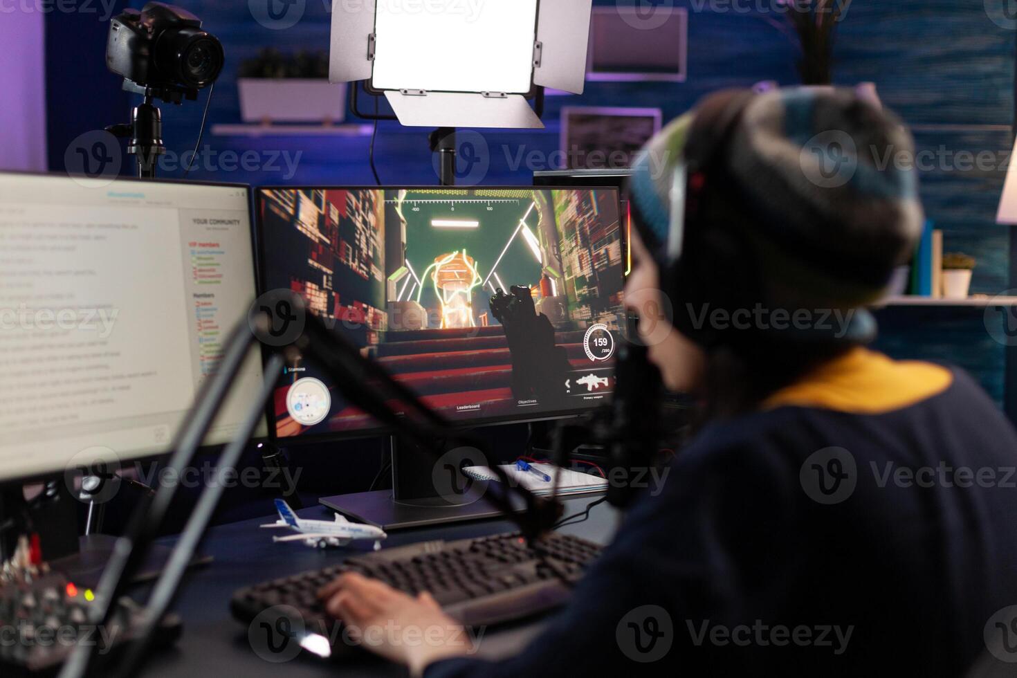 Woman live streaming games on monitor with chat. Person showing gameplay on online stream, using microphone, headphones and modern equipment to play. Streamer gaming live at desk photo