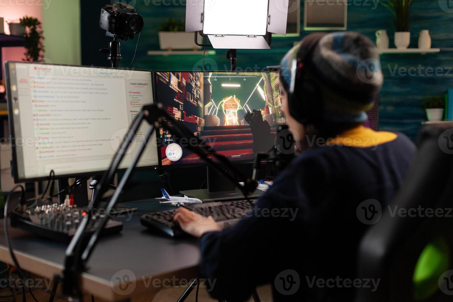 Player doing online live streaming with games. Woman using gameplay on computer to stream and looking at monitor with chat. Person broadcasting and playing games with microphone. photo