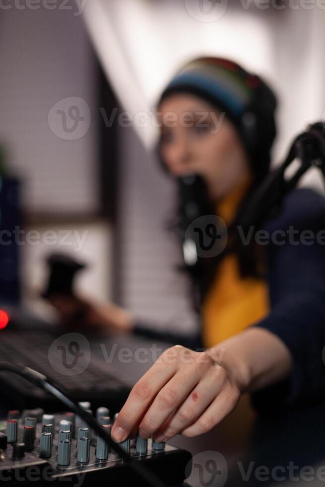 Close up of woman using streaming equipment live with headphones and microphone. Gamer talking to audience on online broadcast, live streaming on computer. Streamer with electronic gadget photo