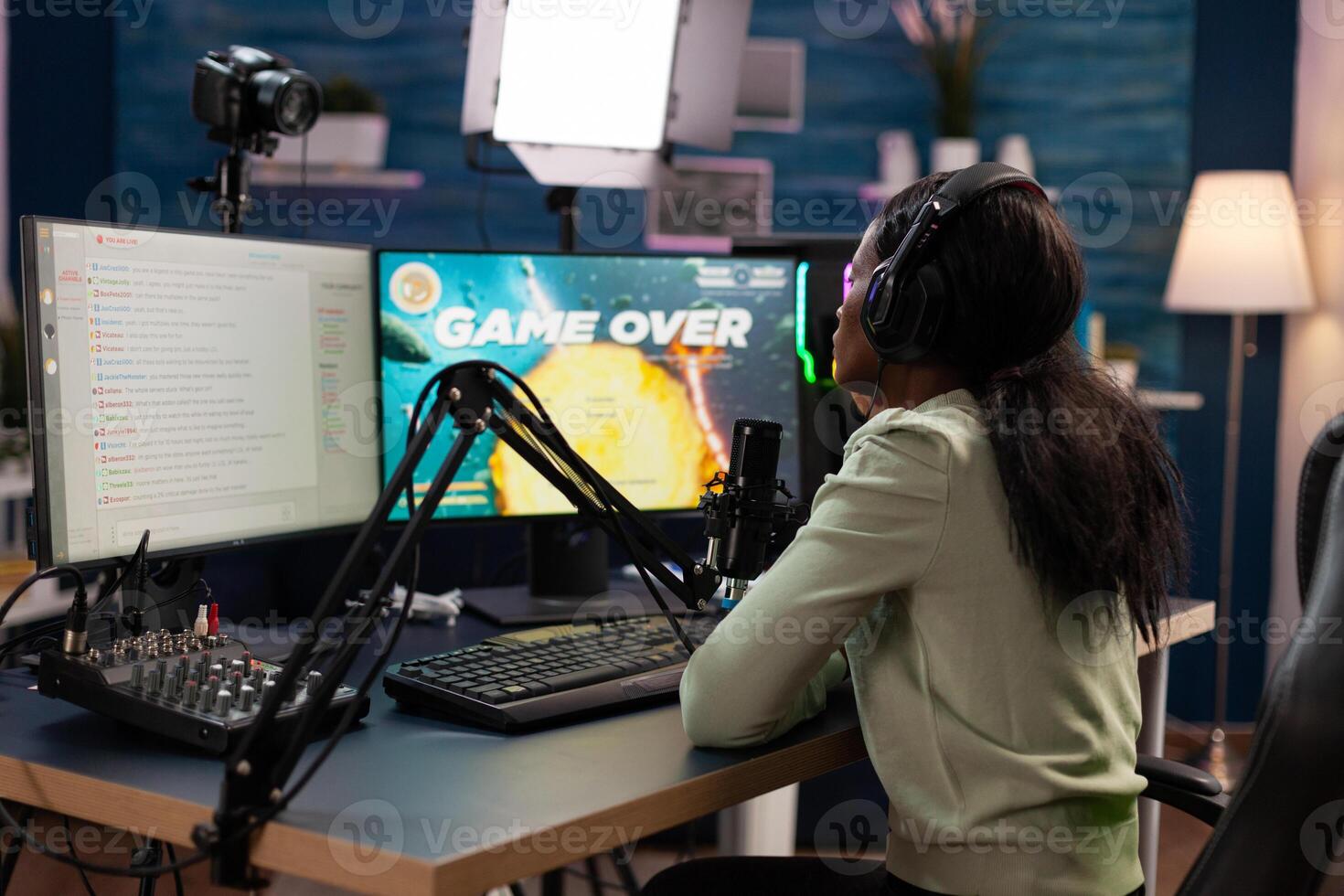 Sad nervous pro gamer sitting at gaming desk playing space shooter videogames losing online games championship. Upset esport woman streaming live using RGB computer equipment, Game over on screen photo