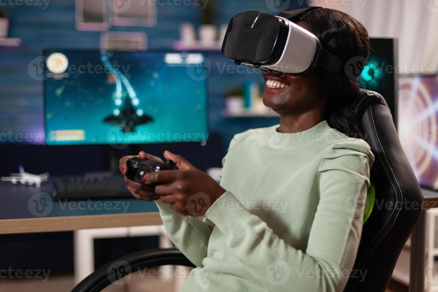 Focused african american pro gamer woman with virtual reality googles playing space shooter videogames using gaming controller during online tournament. RGB computer equipment. Cyber space photo