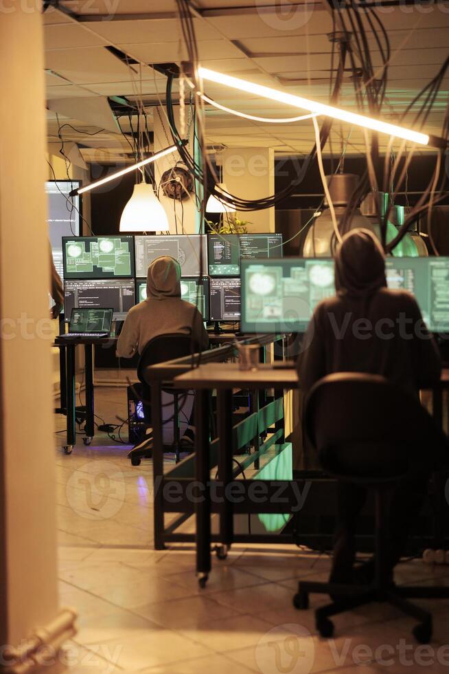Hackers planting computer malware on software, cracking database password and stealing information for ransom. Having access to online server illegally, cybercrime at night time. photo