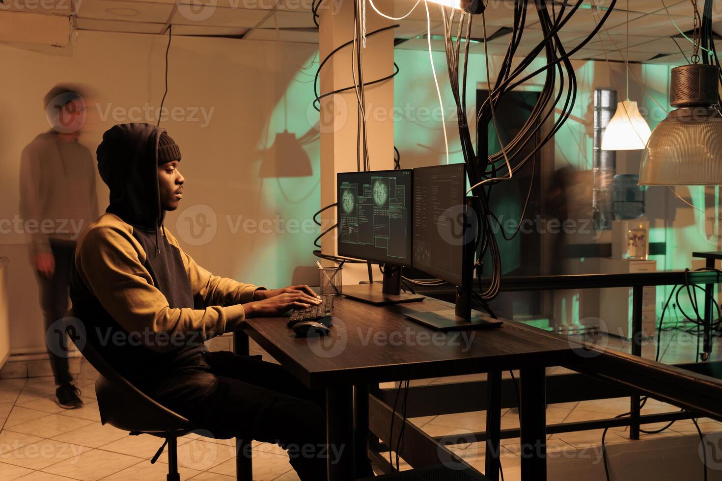 African american hacker working on spyware with encryption, causing security breach alert and accessing sensitive information for ransom. Young man hacking database server with code. photo
