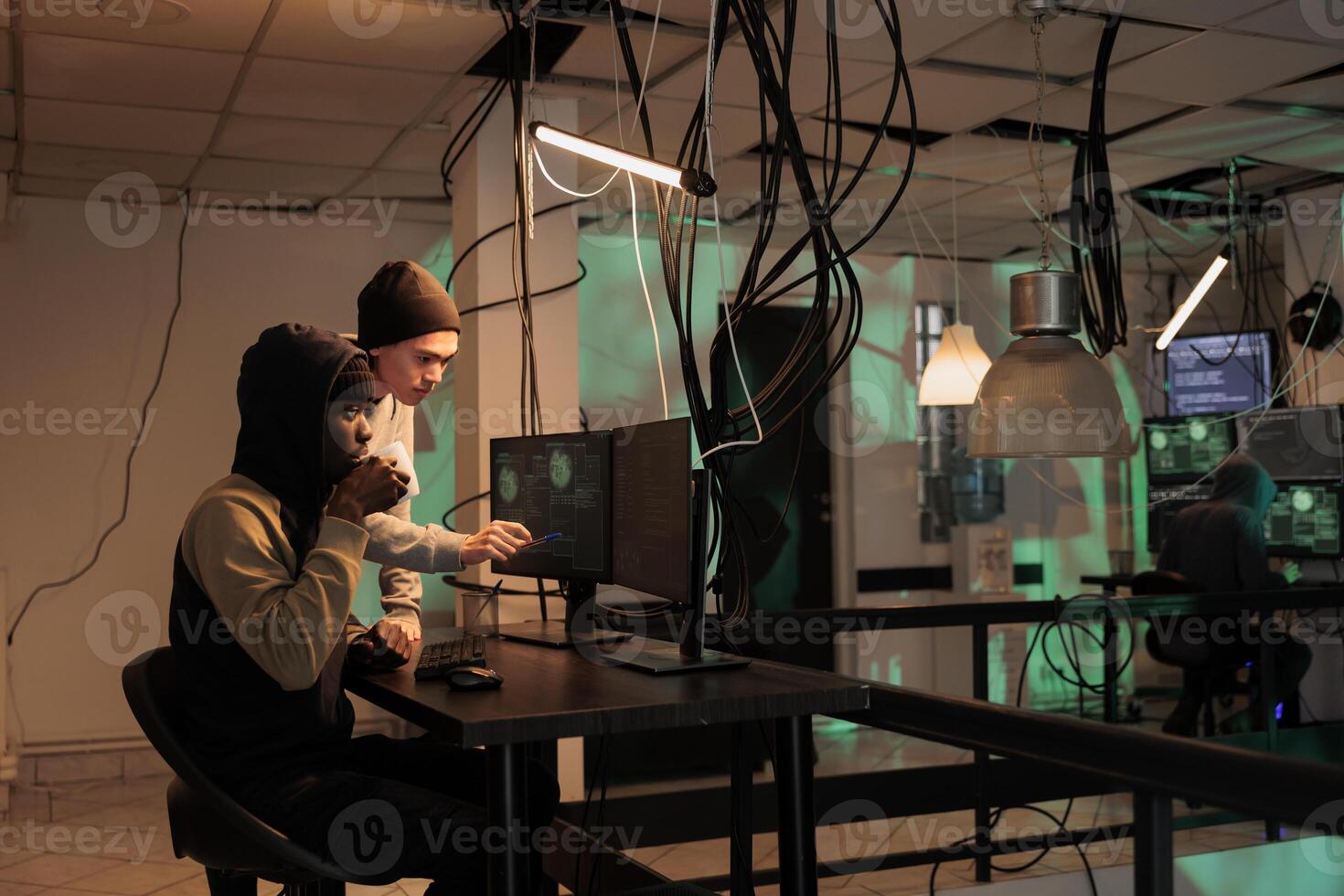 Hackers group coding internet virus program, developing malicious software, criminals stealing privacy information. Cybercrime, scammers hacking computer system, breaking into database at night time photo