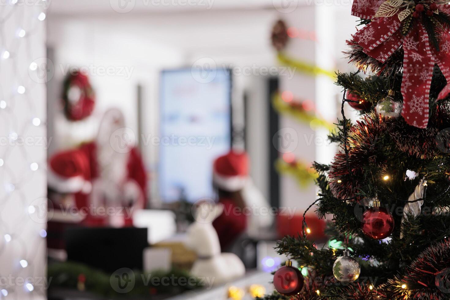 Special occasion decorated Christmas tree close up with management executive holding meeting with employees in blurry background. Xmas ornate boardroom used for discussing financial statistic charts photo