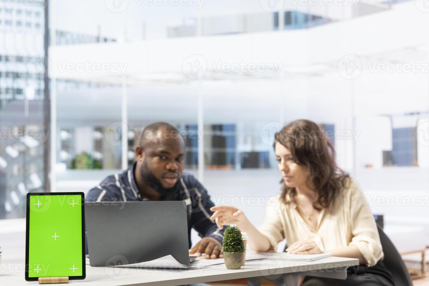 Entrepreneur examining blueprints with a real estate agent next to isolated tablet display. Woman realtor and client negotiating leasing contract terms for a high class office space. photo
