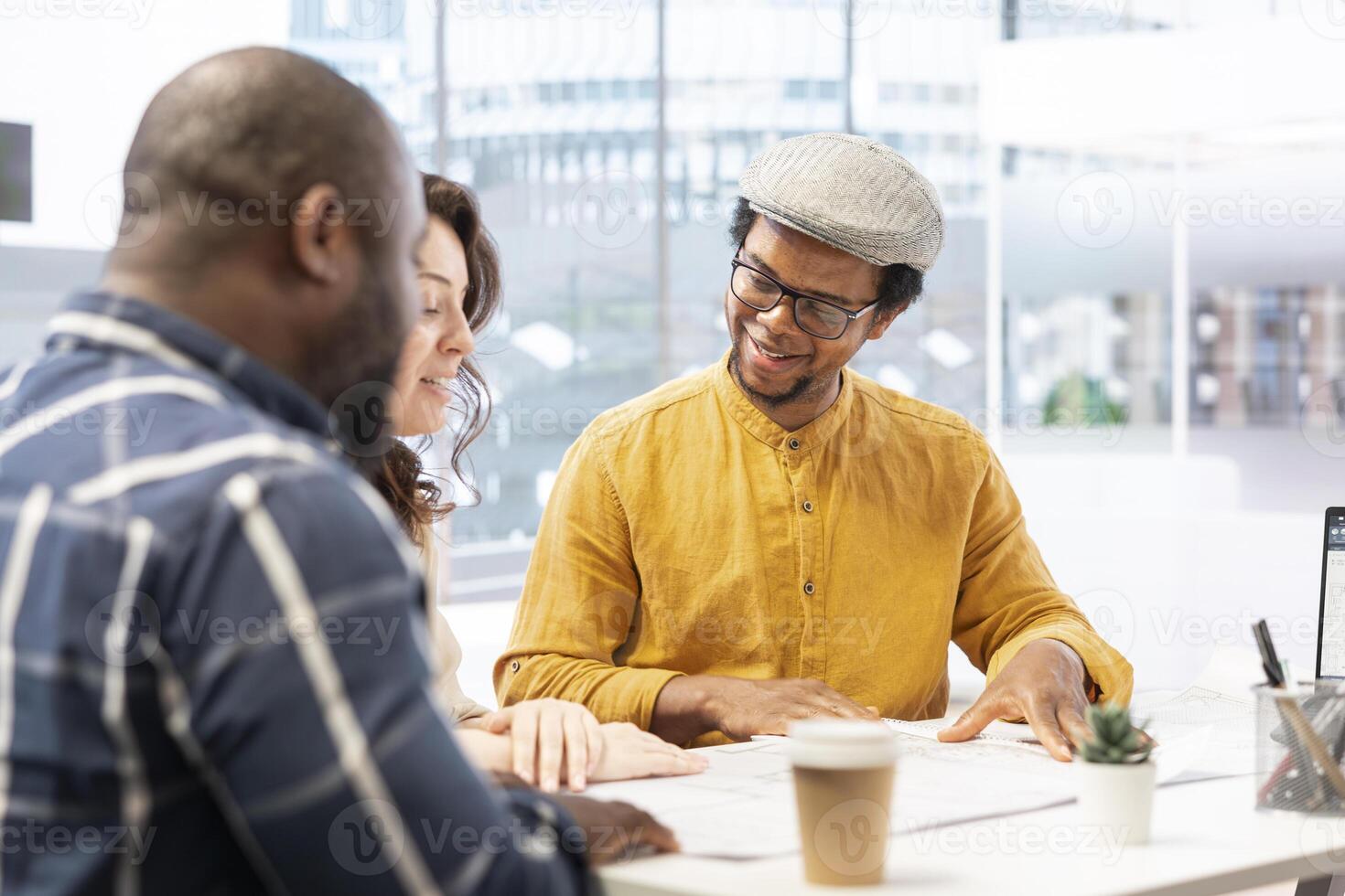 Realtor meeting with entrepreneurs to establish leasing contract terms after evaluating architectural blueprints with clients at desk. Business people negotiating for an investment strategy. photo