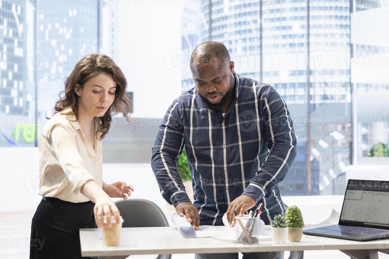 Real estate agent guides client through an urban property tour, focusing on the architectural blueprints to present the property layout. Strategy planning for a modern office space investment. photo