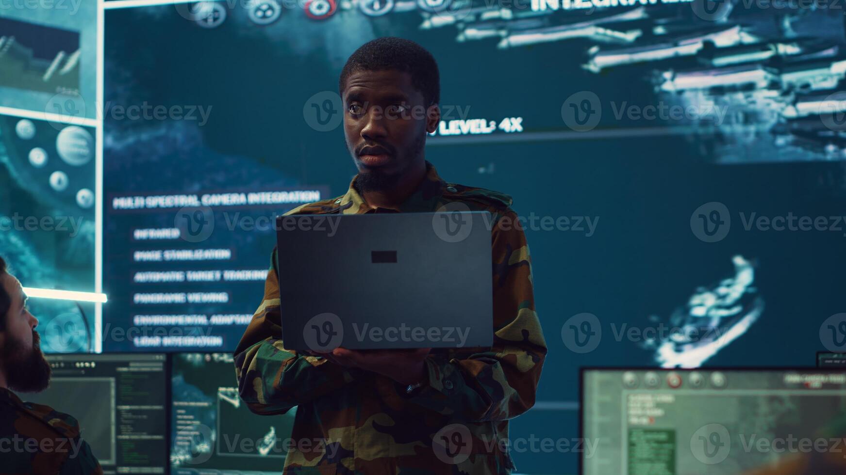Infantry unit leader examines big data on a screen in military monitoring room and command center. Male army officer ensures national safety, strategic and tactical intelligence. Camera A. photo