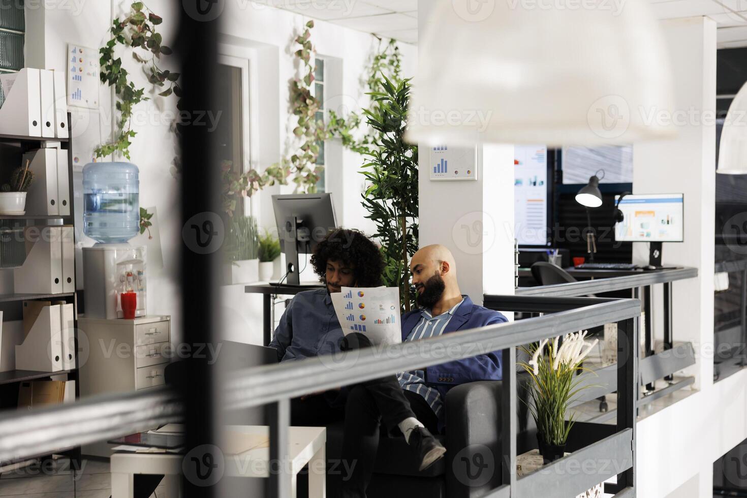 Two corporate employees discussing financial analysis and planning presentation in coworking space. Arab company analysts working in office, holding papers with charts and graphs photo