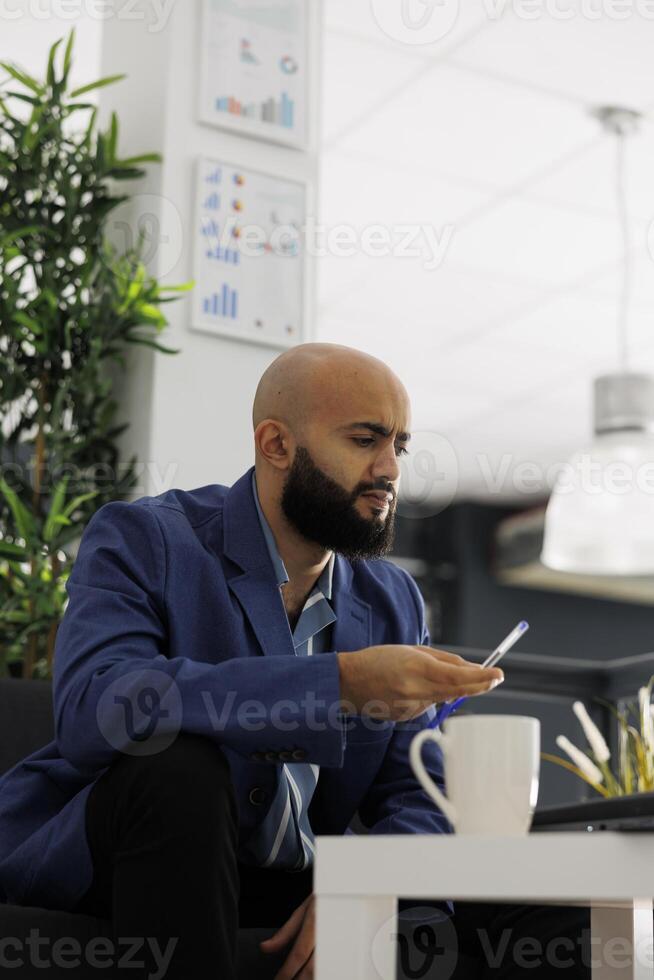 Arab financial manager working on laptop, analyzing data and developing strategies for company. Start up entrepreneur creating business plan and solving complex task in coworking space photo