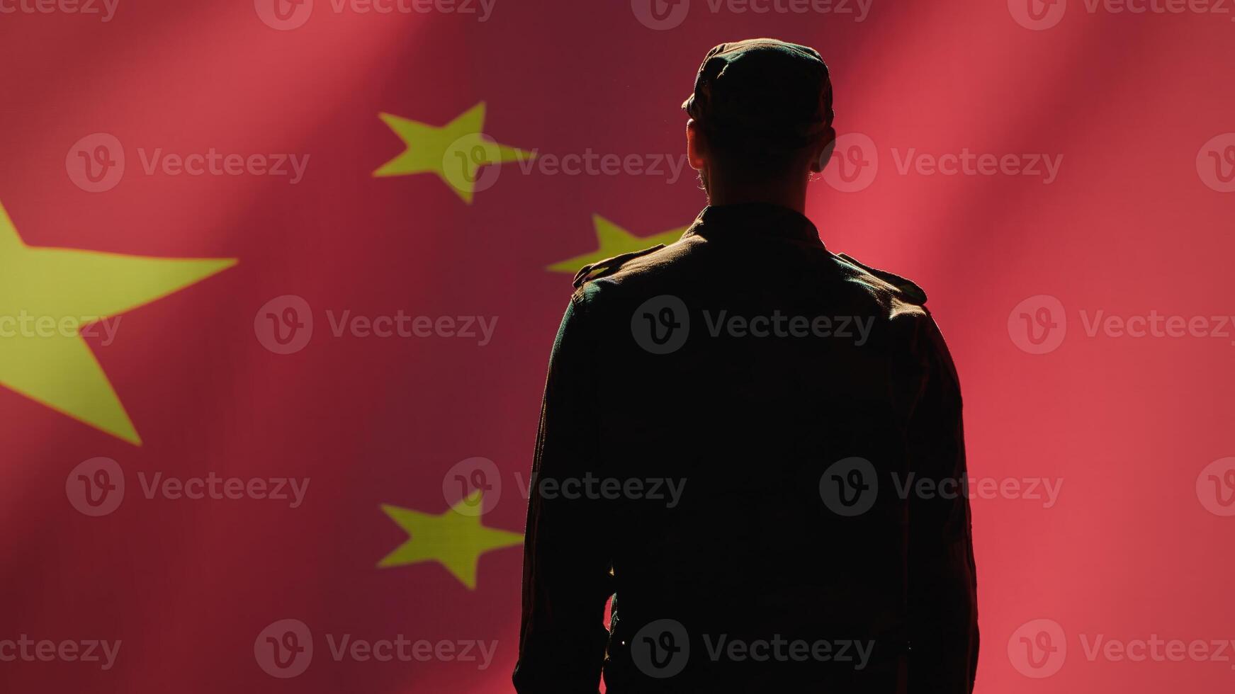Soldier doing salute hand gesture towards Chinese flag, feeling pride in serving country. China army personnel does military greeting gesturing while listening national anthem, camera A photo