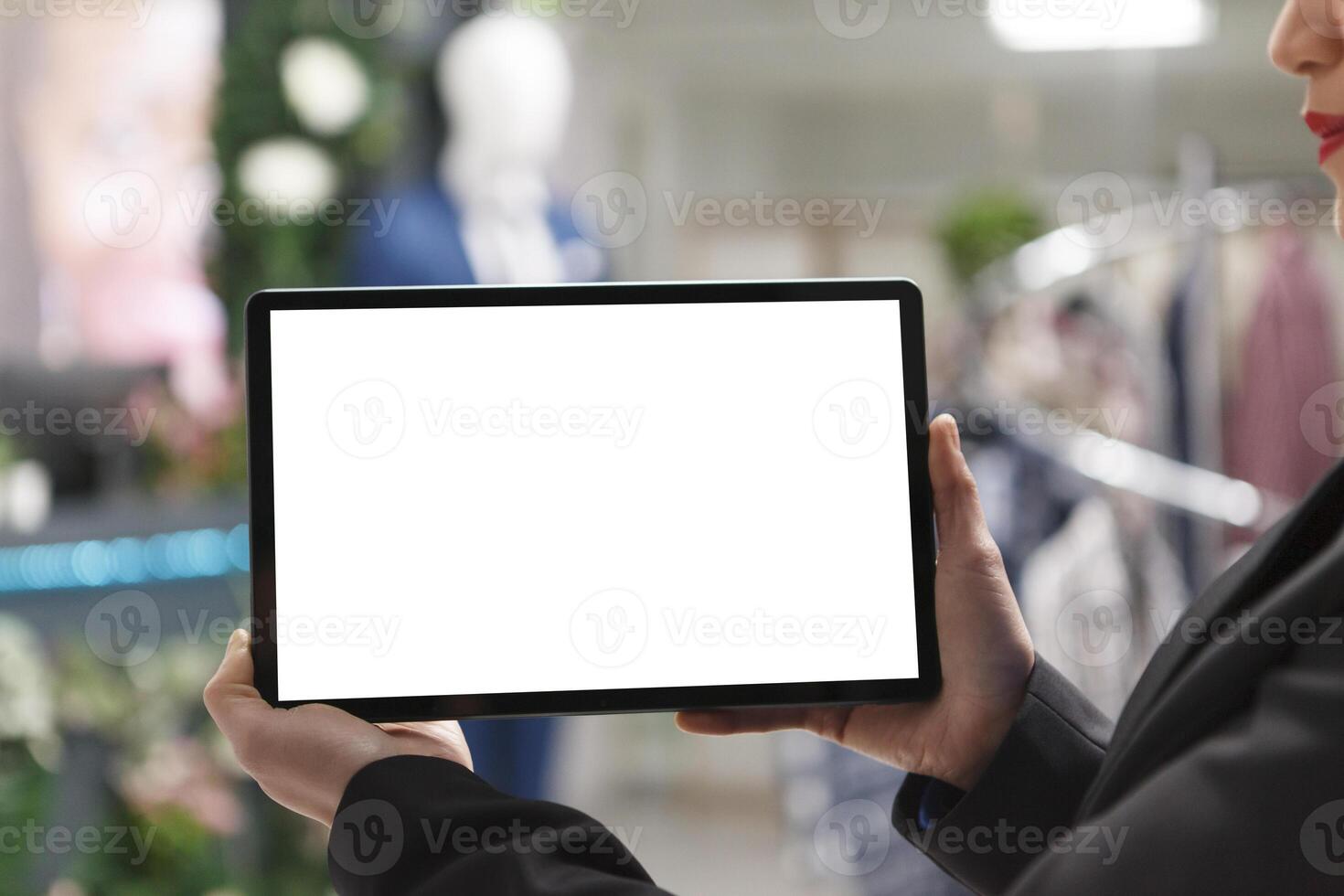 Woman hands holding digital tablet empty white touchscreen mockup closeup in clothing store. Shopping department mall consultant using portable gadget with blank screen for app photo