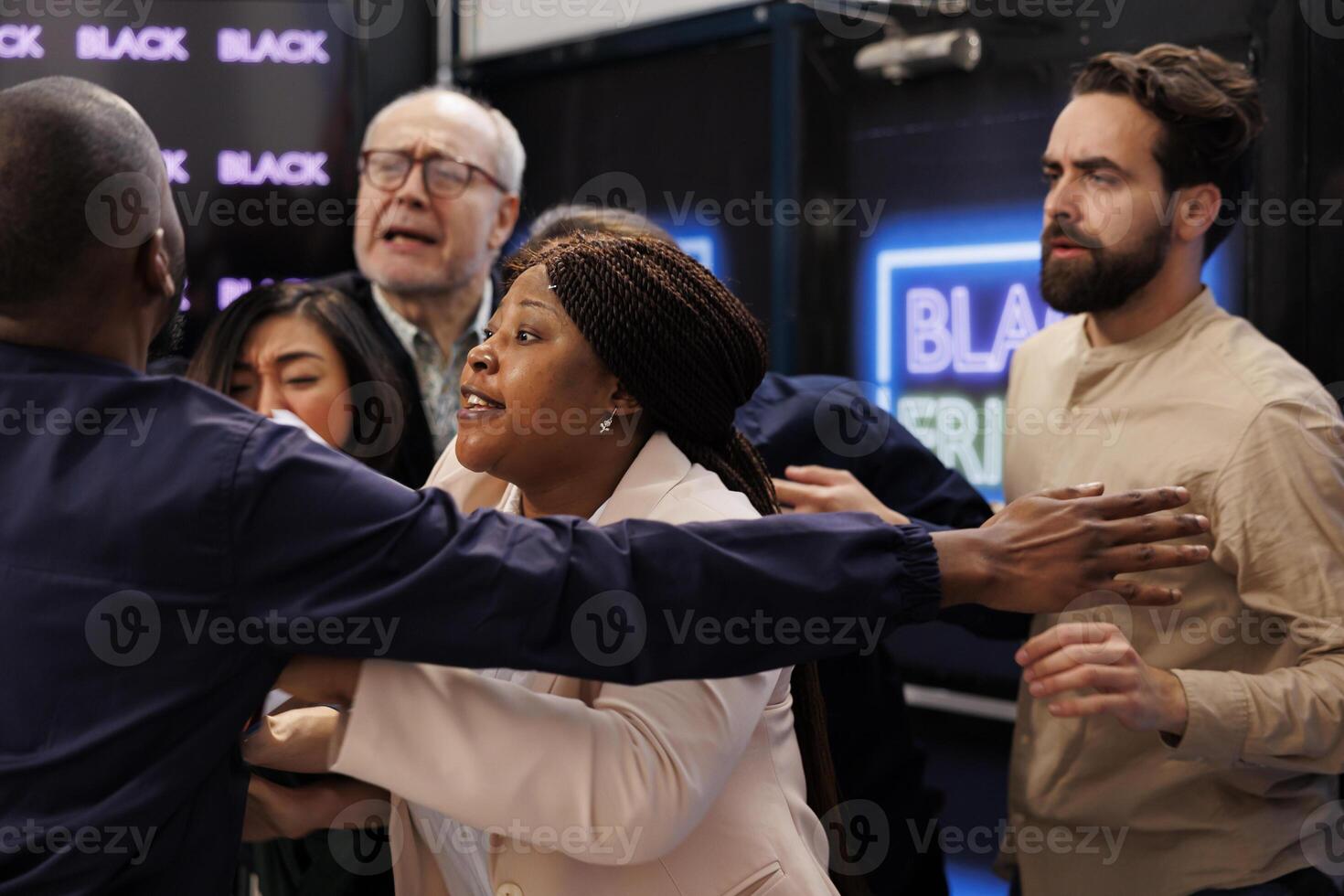 People shoppers going crazy to get to store first in order to get best deals during Black Friday sales. Angry crowd of customers fighting with security officer while waiting at shopping mall entrance photo
