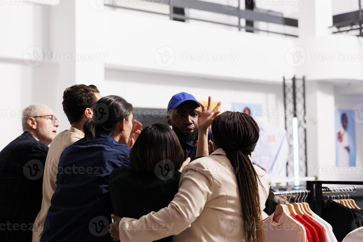 Security officer handling crowd and reducing violence while patrolling fashion store entrance. Frenzied shoppers fighting with shopping mall worker while waiting in line for Black Friday sales photo