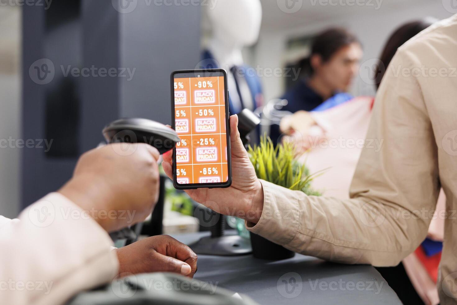 Digital coupon marketing. Customer using mobile discount code while shopping in clothing store on Black Friday, close up of man showing smartphone with digital voucher to retail employee at checkout photo