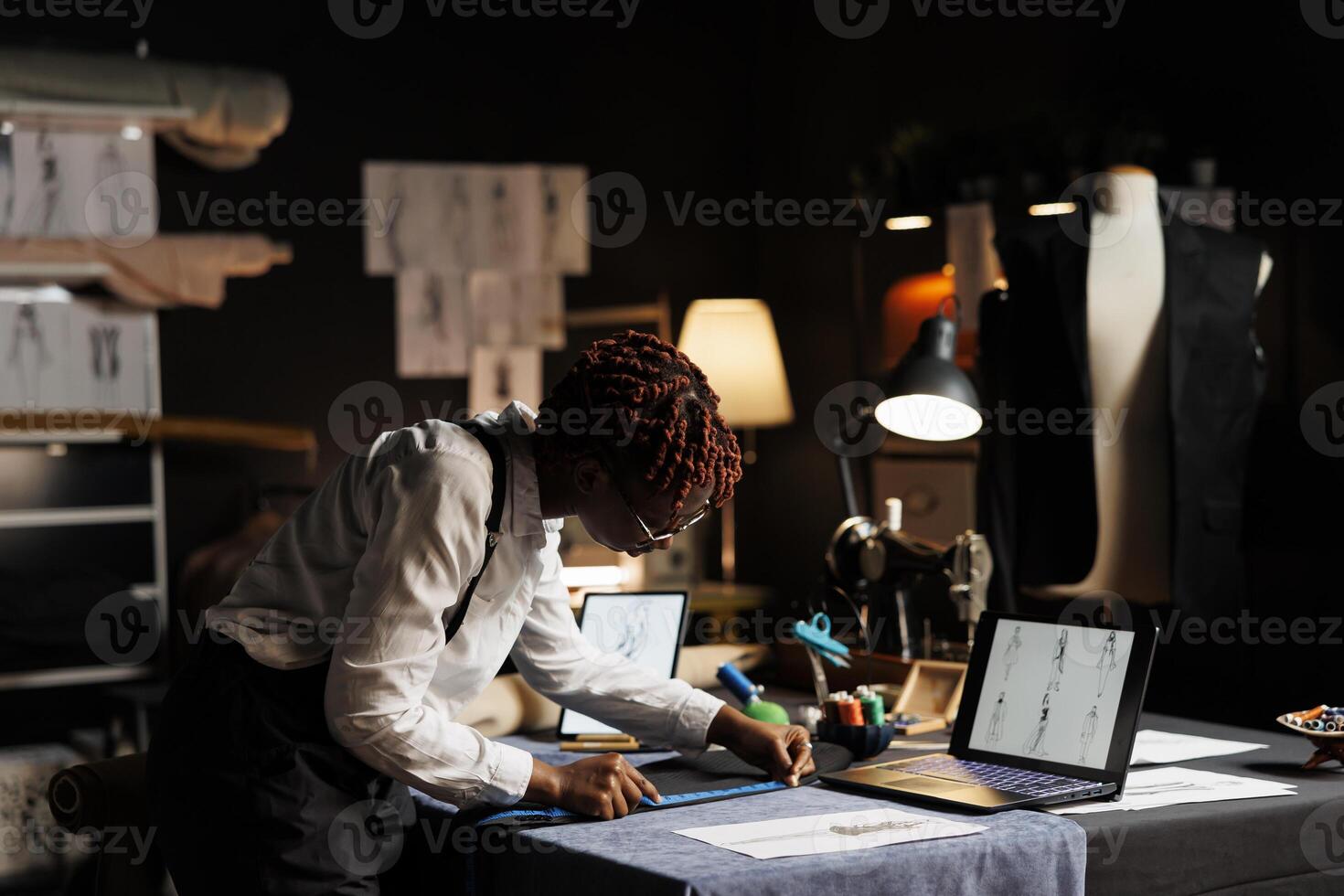 Precise seamstress meticulously measuring exquisite suit blazer using tape. Experienced tailor in atelier shop workspace checking bespoken sartorial garment fits customer photo