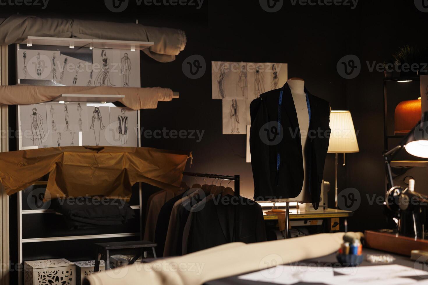 Upscale professional atelier shop full of premium quality elegant sartorial outfits and fashion design sketch drawings on walls. Tailoring studio with bespoken stylish clothing on mannequins photo