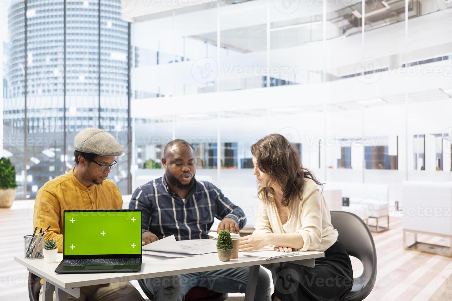Businessman discussing with the real estate agents next to chroma key on laptop, meeting to negotiate leasing contract terms before looking at blueprints for an office relocation. photo