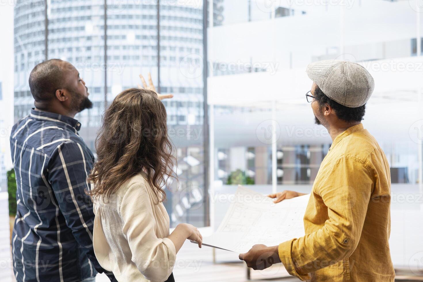 Business clients and broker salesman examining blueprints and layout during an office tour, planning leasing contract and investment strategy for startup development. Office hunt. photo