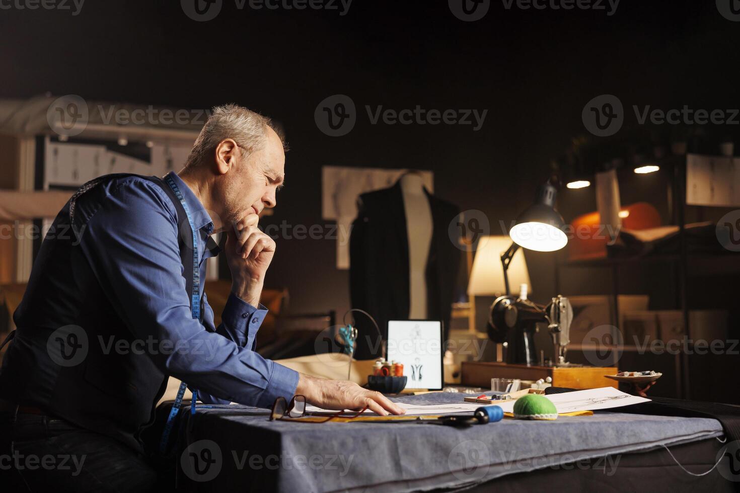 Upset fashion designer unable to come up with inspiration for upcoming sartorial runway show project. Elderly couturier overthinking in tailoring studio, looking for perfect bespoken outfit photo