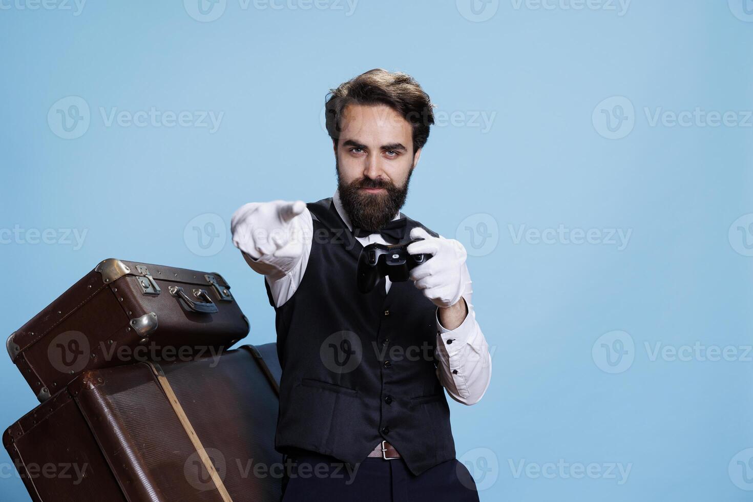 Bellhop celebrates videogames win in studio, gaming posing with remote controller and being pleased about winning online gaming play. Confident doorman having fun with competition. photo