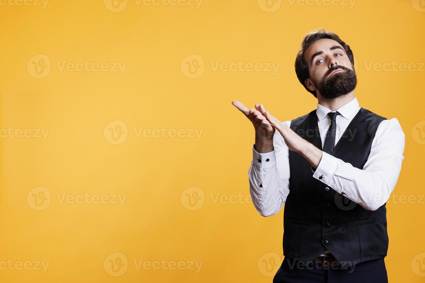 Elegant skilled man applauding someone on camera, clapping hands to cheer for person in studio. Happy positive waiter feeling optimistic trying to boost confidence after success. photo