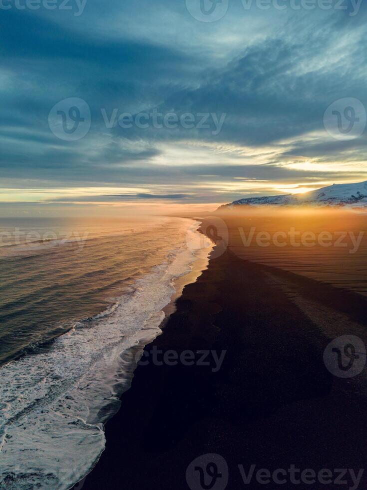 Aerial view of nordic black sand beach in iceland, beautiful ocean shoreline and beachfront at sunset, creating magical icelandic scenery. Majestic atlantic coast with huge waves smaking. photo